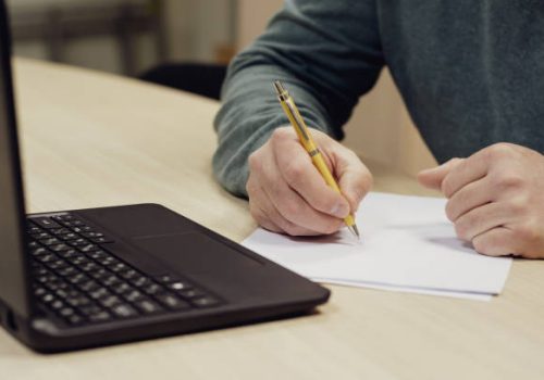 a white man in the process of writing notes on a piece of paper important information. writer at work